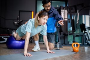 Personal Trainer: Asian man and woman working out, one is a trainer, the other is an exerciser